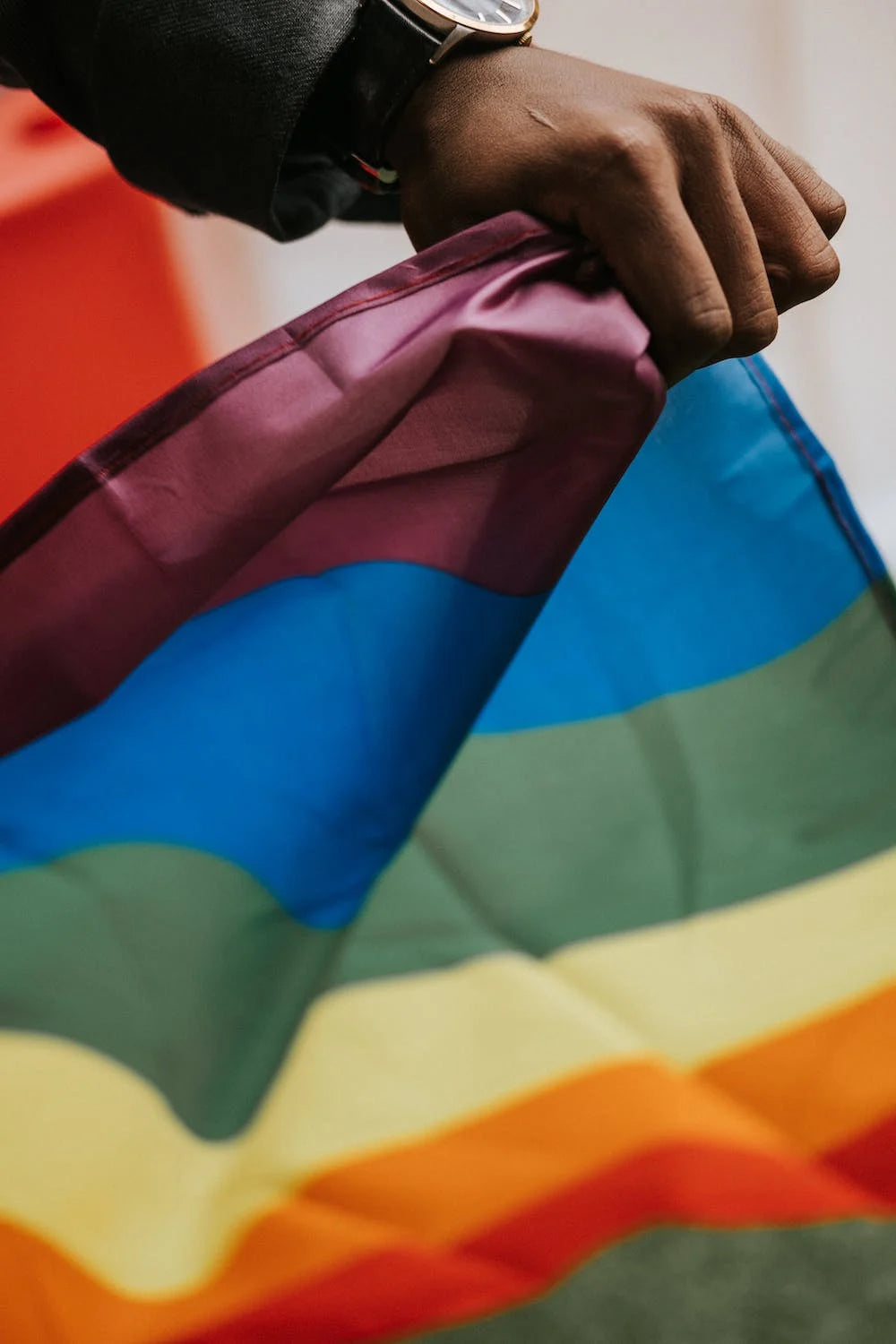 BIPOC Person holding the Pride Flag with Pride!